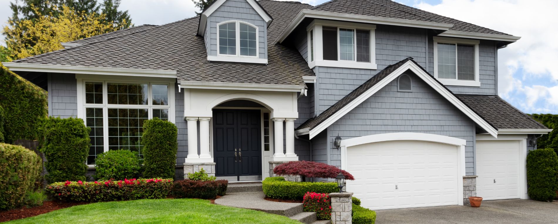 A view to house with a frontyard and double garage door